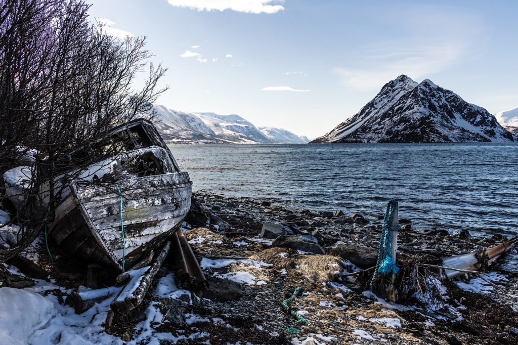 Gammel og ødelagt båt i fjæra
