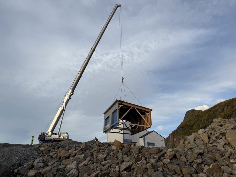 En kran løfter en ny modulbygning på plass under utbyggingen ved Osan gjenvinningsstasjon. En arbeider i gul refleksdrakt står i nærheten og følger arbeidet.